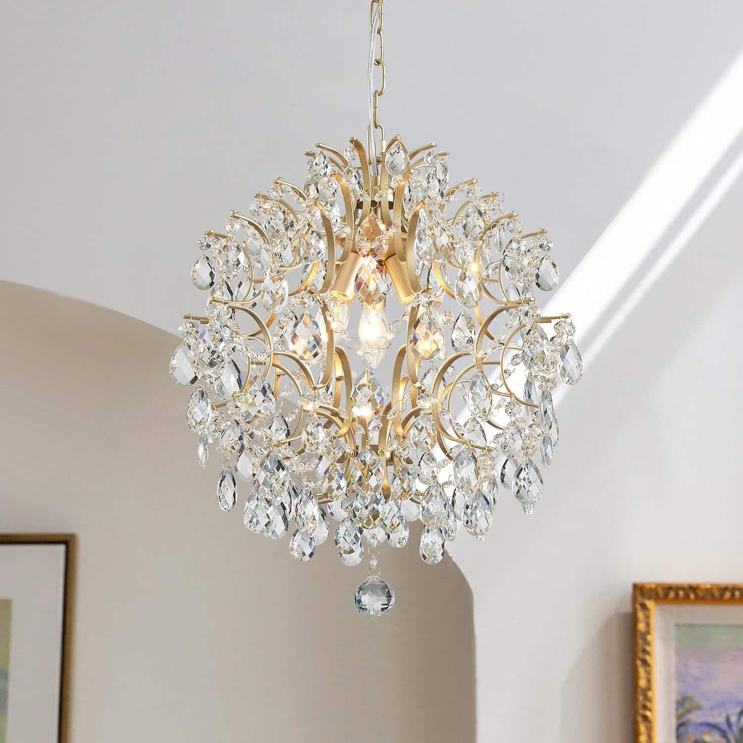 Gold crystal raindrop chandelier with modern pendant design hanging in a dining room.